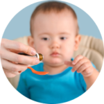 mom-pours-syrup-with-medicine-into-spoon-toddler-reaches-spoon-with-medicine